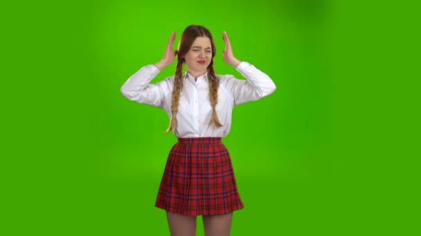 Schoolgirl closes his ears from the noise . Green screen — Stock Video