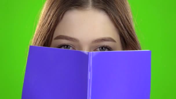 Školačka zakryla tvář s fialovým notebookem. Zelená obrazovka. Detailní záběr — Stock video