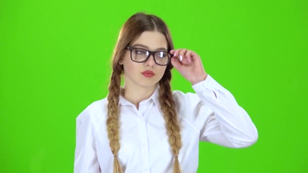 La colegiala con falda a cuadros se quita las gafas y bosteza. Pantalla verde — Vídeo de stock