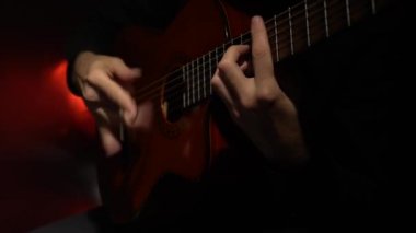 Gitar çalmak bir melodi adam. Yakın çekim. Arkadan ışık
