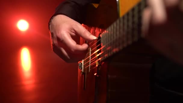 Gitarre spielt ein Melodiemann. Nahaufnahme. Licht von hinten — Stockvideo