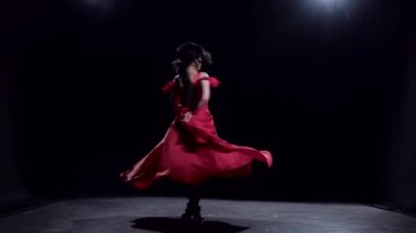 Karanlık odada kadın zarif hareketleri dans gerçekleştirir. Siyah arka plan