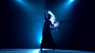 Kız onun elinde bir manton ile dans ediyor. Arkadan llight. Duman arka plan. Siluet