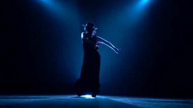 Kadın dans onun elinde kastanyet ile dans ediyor. Arkadan llight. Koyu arka plan. Siluet