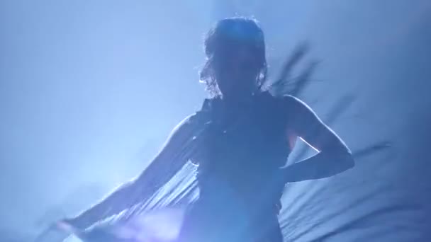 La ragazza sta ballando con un manton. Luminoso da dietro. Sfondo di fumo. Silhouette — Video Stock