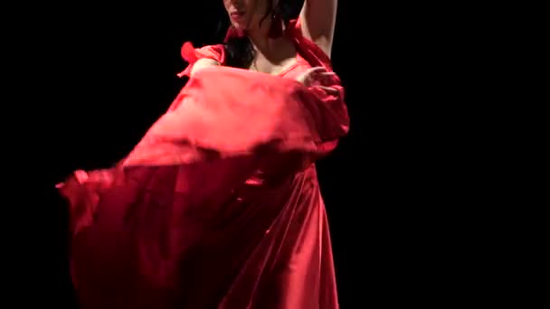 Flickan spinning i en röd klänning. Svart bakgrund — Stockvideo