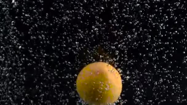 Oranje valt onder het water op luchtbellen in het water geïsoleerd op zwarte achtergrond — Stockvideo
