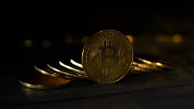 Bitcoins avuç birbirinin üstüne bir siyah altın arka plan bokeh bir kenarında duran bir masaya yığılmış. Yakın çekim