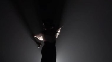 Şapkalı bir kadın Arjantinli dans kastanyet ile dans ediyor. Arkadan ışık. Duman arka plan. Ağır çekim