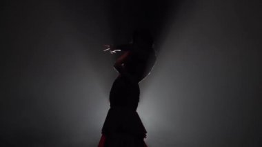 Kadın akan hareketleri el ile dans ediyor. Arkadan ışık. Duman arka plan. Ağır çekim. Siluet