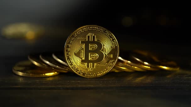 Koin-koin bitcoin emas terletak beberapa genggam di atas meja gelap dengan latar belakang kabur. Tutup. — Stok Video