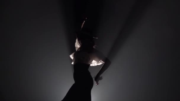 Girl is dancing with castanets and her leg is tugging at the tail of the dress. Light from behind. Smoke background. Slow motion — Stock Video
