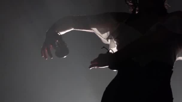 Dziewczyna w jej ręce trzyma kastaniety i tańczy taniec. Światło z tyłu. Tle dymu. Zwolnionym tempie — Wideo stockowe