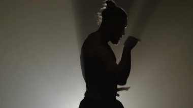 Adam bir striptiz dans ediyor. Siyah arka plan. Siluet. Ağır çekim