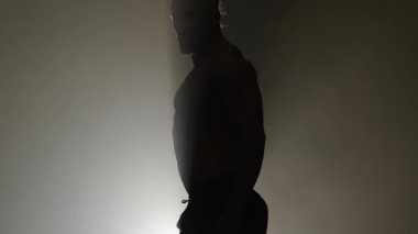 Adam bir striptiz dans ediyor. Siyah arka plan. Siluet. Ağır çekim