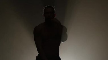 Adam bir striptiz dans ediyor. Siyah arka plan. Siluet. Ağır çekim