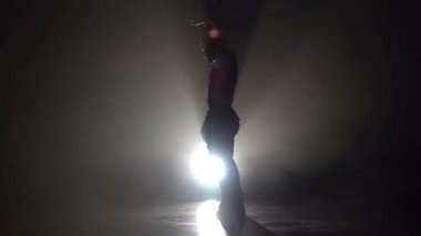 Adam bir striptiz dans ediyor. Siyah arka plan. Siluet. Ağır çekim
