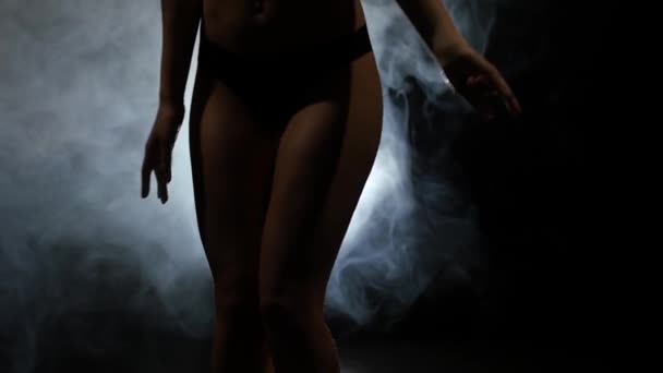 Stripper met piercing in de navel dansen. Zwarte achtergrond. Silhouet. Slow motion — Stockvideo