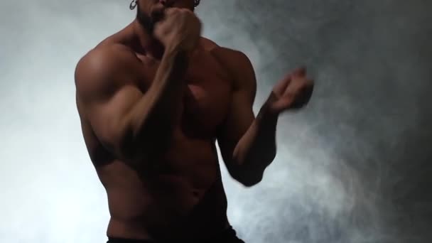 Aufgepumpter Typ tanzt einen sexy Tanz. schwarzer Rauchhintergrund. Zeitlupe — Stockvideo