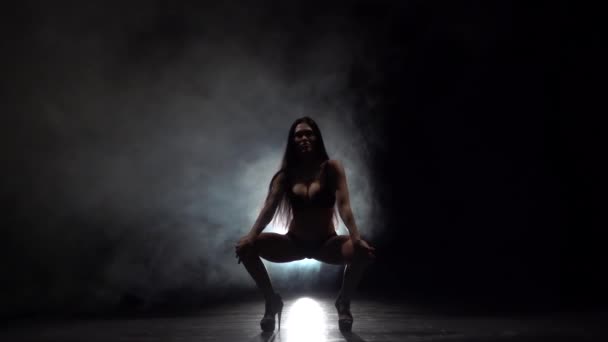 Танцівниця виконує сексуальні рухи. Чорний дим фону. Повільний рух — стокове відео