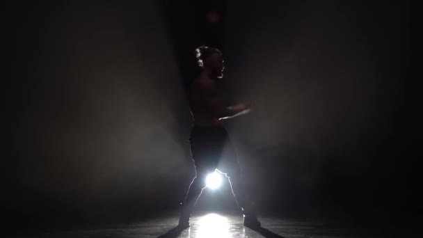 Man is een strip dansen. Zwarte achtergrond. Silhouet. Slow motion — Stockvideo