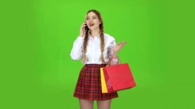 Liseli kızlar telefonda konuşuyor ve alışveriş torbaları tutar. Yeşil ekran. Ağır çekim