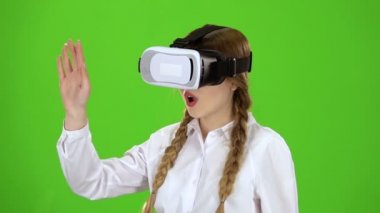 Sanal gerçeklik Gözlüklü kız bir heyecan verici video yeşil ekran izliyor. Ağır çekim