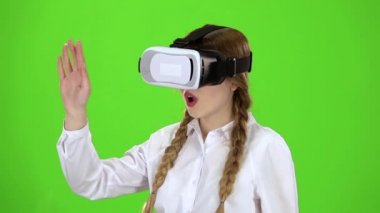 Sanal gerçeklik Gözlüklü kız bir heyecan verici video yeşil ekran izliyor. Ağır çekim