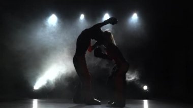 Kız onların fikir tartışması kickboks bir adamla tekme atıyor. Arkadan ışık. Duman arka plan