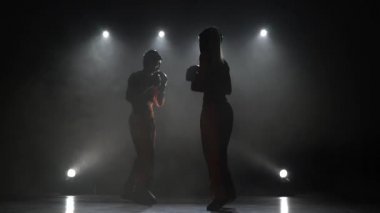 Adam kask ve boks eldivenleri karanlıkta ringde yenerek bir kızla. Arkadan Silhouette.Light. Duman arka plan
