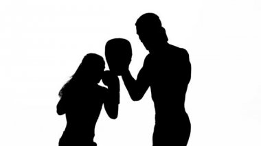 Kickboks boks pençeleri üzerinde doğrudan darbeler dışında kız çalışma ayakları onları tutan adam yener. Siluet. Beyaz arka plan
