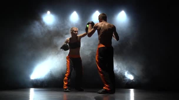 Küzdelem a srác és a lány a boksz-a paws. Fény hátulról. Füst háttér — Stock videók