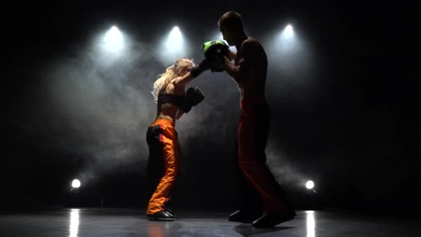 Desenvolvimento de chutes retos kickboxing em patas de boxe. Luz por trás. Fundo de fumo — Vídeo de Stock