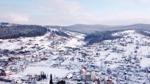 Dorp met gebouwen en een zichtbare kerk alle bedekt met sneeuw. Luchtfoto — Stockvideo