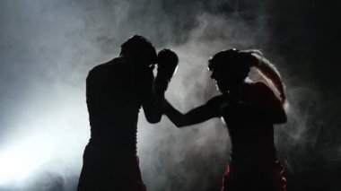 Kadın bir adam onların fikir tartışması kickboxing ile tekme atıyor. Duman arka plan. Siluet. Ağır çekim