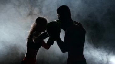 Karanlıkta ringde yenerek kız boks eldivenli adam. Siluet. Duman arka plan. Ağır çekim