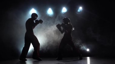 Kız kickboks için fikir tartışması adam vuruyor. Duman arka plan. Siluet. Ağır çekim