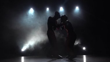 Kız kickboks için fikir tartışması adam vuruyor. Duman arka plan. Siluet. Ağır çekim