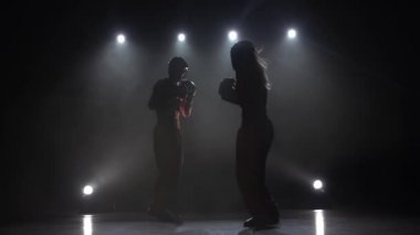Kadın bir adam onların fikir tartışması kickboxing ile tekme atıyor. Duman arka plan. Siluet. Ağır çekim