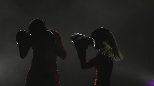 El tipo con una chica se está preparando para una competencia de kickboxing. Silueta. Fondo de humo. Movimiento lento — Vídeos de Stock