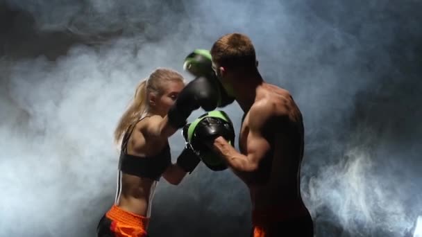 Desarrollo de patadas rectas kickboxing en las patas de boxeo. Luz por detrás. Fondo de humo. En cámara lenta. Movimiento lento — Vídeo de stock