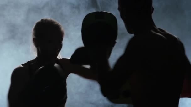 Treinador de homens e a rapariga do boxe. Luz por trás. Silhueta. Fundo de fumo. Movimento lento — Vídeo de Stock