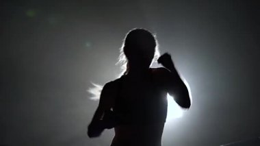 Atlet trenler karanlık bir yüzük ringde bir spot ışığı parlıyor. Siluet. Arkadan ışık