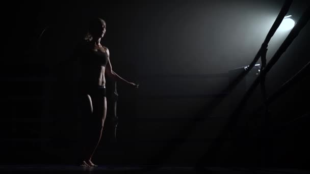 Femme sautant de la corde dans un anneau sombre. Silhouette — Video