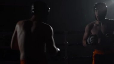 Kask ve boks eldivenleri karanlıkta ringde dayak iki adam