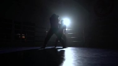 İki adam karanlıkta ringde mücadele