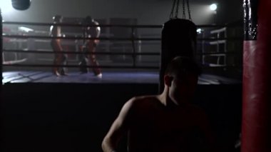 Eldiven erkeklerde işte kickboxers fikir tartışması ringde arka planda bir armut atıyor. Ağır çekim