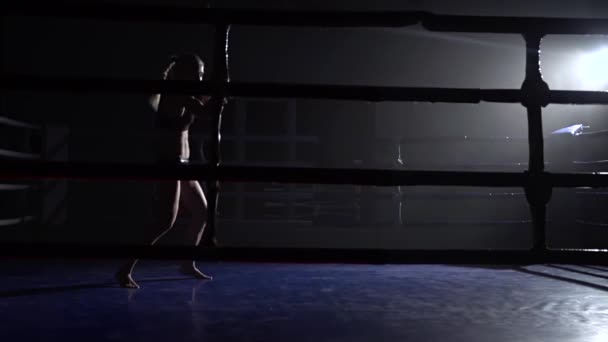 Athlete trains in the dark ring beats her legs . Silhouette. Slow motion — Stock Video