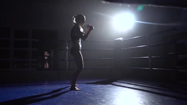 Atleta en un ring vacío está pateando. Silueta. Movimiento lento — Vídeo de stock