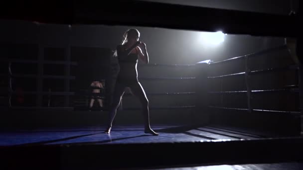 Kickboxer lány a ringben ütéseket, kezét-lábát. Sziluettjét. Lassú mozgás — Stock videók